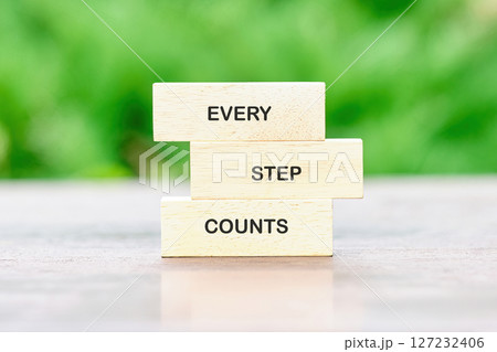 Concept text EVERY STEP COUNTS painted on wooden blocks on a bright green background, reflecting the peaceful atmosphere outdoors 127232406
