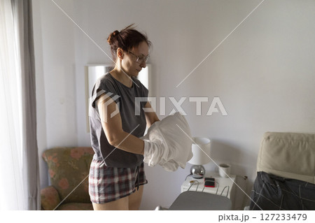 Housewife arranging pillowcase before ironing in bedroom Housewife arranging pillowcase before ironing in bedroom 127233479