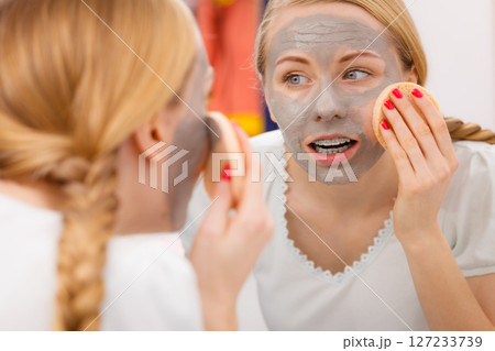 Woman removing mud facial mask with sponge Woman removing mud facial mask with sponge 127233739