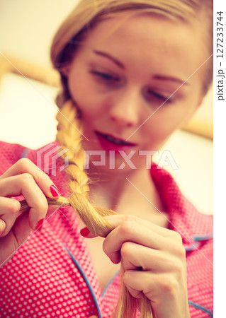 Closeup of woman doing braid on blonde hair 127233744