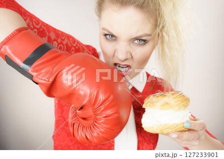 Woman fighting off bad food, boxing cream puff cake 127233901