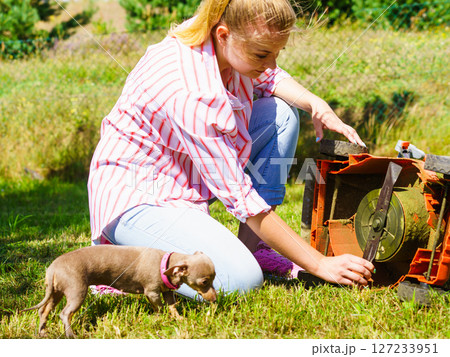 Female gardener with broken lawnmower 127233951