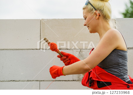 Woman using string as level in wall construction. Woman using string as level in wall construction. 127233968