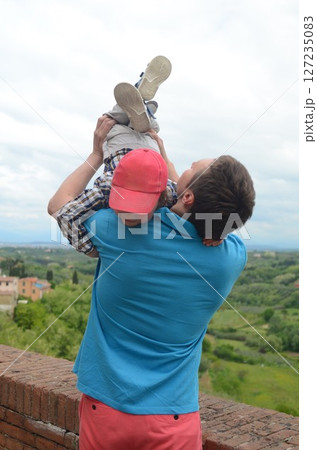 Father Lifting Son in Air with Scenic Landscape View Father Lifting Son in Air with Scenic Landscape View 127235083