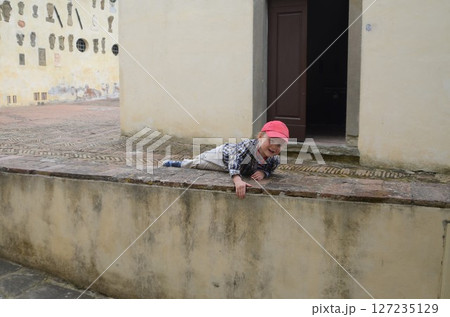 Child Playing on Stone Wall with Joyful Expression 127235129