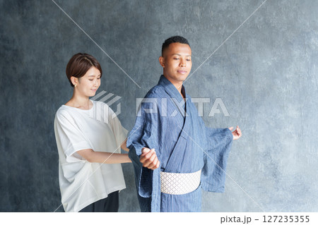 外国人観光客に浴衣を着付けるスタッフ 127235355