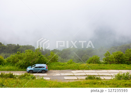 perechyn, ukraine - 22 ju2 2019: 4wd car on a countryside mountain road. family suv for weekend on the hillside. mountain landscape of carpathian alps on a foggy morning in summer. vacation memories 127235593
