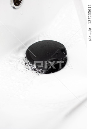 This is a closeup picture capturing a sink drain with water flowing out of it 127235612