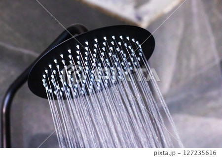 A sleek black shower head with refreshing water flowing out of it 127235616
