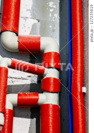 A long row of red and white pipes mounted on a wall surface 127235619