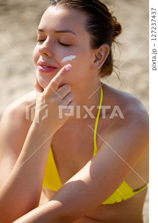 Skin care.Sun protection. Beautiful woman in bikini apply sun cream on Face. Woman with Suntan lotion on beach. Portrait of female holding moisturizing sunblock. The girl uses sunscreen for her skin Skin care.Sun protection. Beautiful woman in bikini apply sun cream on Face. Woman with Suntan lotion on beach. Portrait of female holding moisturizing sunblock. The girl uses sunscreen for her skin 127237437