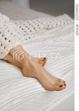 Relaxation and comfort in a cozy bedroom setting with bare feet resting on soft bedding 127238052