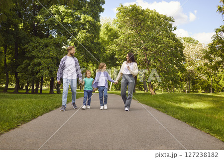 Happy family with two children walking outdoors and talking with each other in summer park. 127238182