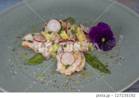 Fresh dorade and shrimp ceviche with avocado, radish, and edible flower on a decorated plate 127238192