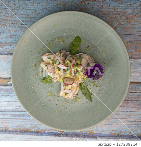Fresh dorade and shrimp ceviche with avocado, radish, and edible flower on a decorated plate 127238214