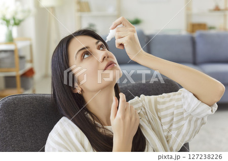 Young woman applying eye drops to relieve dryness, irritation and maintain eye moistened and healthy. Young woman applying eye drops to relieve dryness, irritation and maintain eye moistened and healthy. 127238226