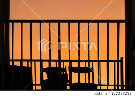 Balcony black fence silhouette in orange sunset sky Balcony black fence silhouette in orange sunset sky 127238252
