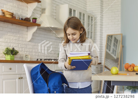 Small pupil holding stack of books packing into backpack organizing before school, learning activity 127238298