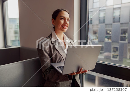 A Professional Woman Diligently Working on Her Laptop in a Modern Office Space Environment 127238307