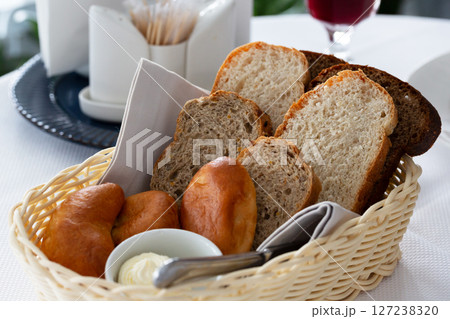 Bread in basket. White and black sliced bread, butter and pies in a basket on the table in the restaurant Bread in basket. White and black sliced bread, butter and pies in a basket on the table in the restaurant 127238320