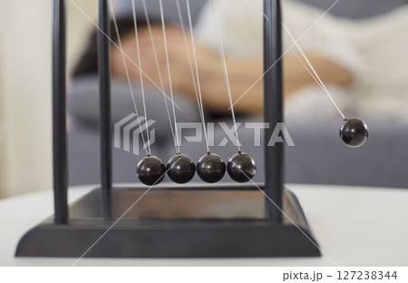 Newton cradle device on desk, balance, perpetual swinging motion, corporate business souvenir 127238344