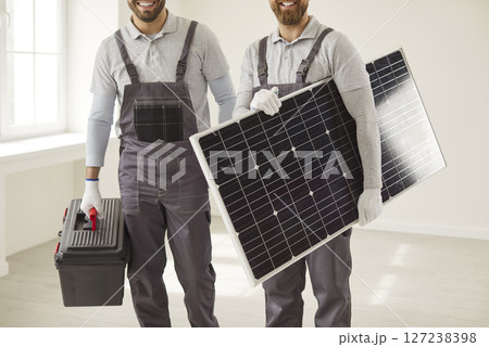 Portrait male workers in uniform holding solar panel indoors working at construction site Portrait male workers in uniform holding solar panel indoors working at construction site 127238398