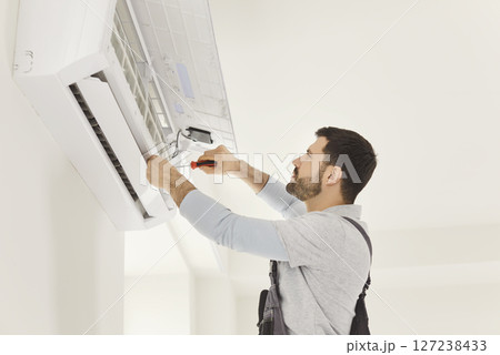Male worker or handyman fixing air conditioning, working in repair service, using screwdriver 127238433