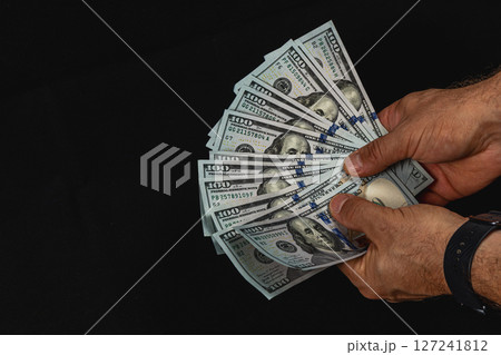 Money being held in hands against a dark background Money being held in hands against a dark background 127241812