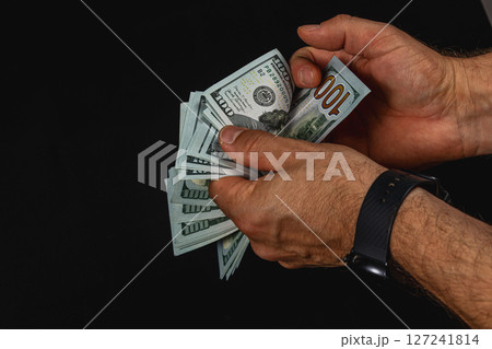 Counting cash in hands with dark background and focus Counting cash in hands with dark background and focus 127241814