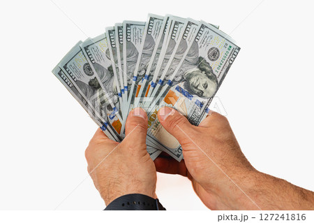 Hands holding a fan of hundred dollar bills in bright light 127241816