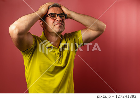 Man expresses frustration against a bright red background 127241892