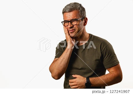 Man expressing concern against a simple backdrop indoors 127241907