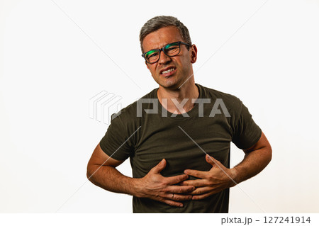Man experiencing discomfort while holding his stomach Man experiencing discomfort while holding his stomach 127241914