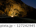 Coastal Night Camp Illuminated Beneath Towering Cliff Wall 127242945