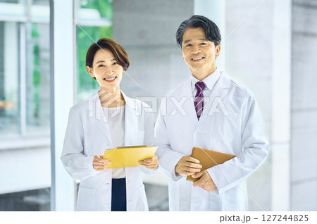 病院の廊下でミーティングする白衣を着た男女の医者 病院の廊下でミーティングする白衣を着た男女の医者 127244825
