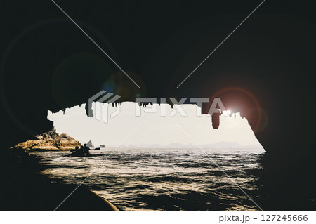 Dark water cave entrance and kayak silhouettes in Thailand 127245666