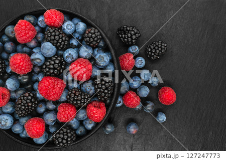 Various berries in round and black cast iron bowl 127247773