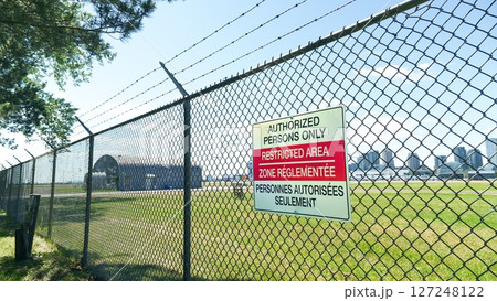 Restricted area with fence boundary and barbed wire, airport secured zone marking. Outdoor Restricted area with fence boundary and barbed wire, airport secured zone marking. Outdoor 127248122