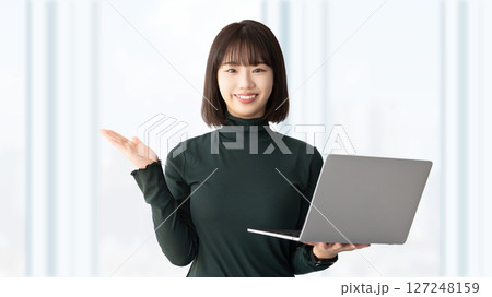 パソコンを持って案内をする笑顔の女性・ビジネスウーマン 127248159