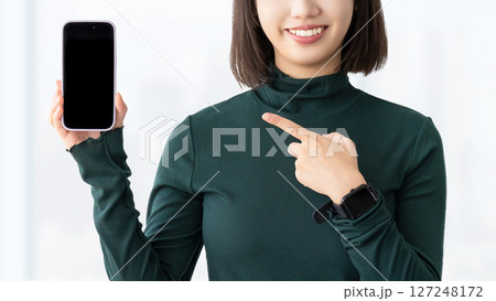 スマートフォンを指差す若い女性・ビジネスウーマン 127248172
