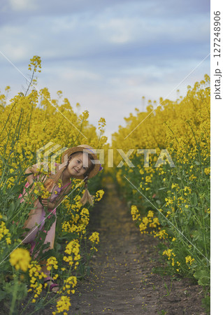charming child in sundress in a rapeseed field charming child in sundress in a rapeseed field 127248906