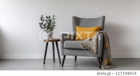 Interior of living room. Gray armchair, green pillow, coffee table and beige wall. Velour Chair against light wall, wooden floor, parquet. Home improvement. Beautiful luxurious modern room settings. 127249014