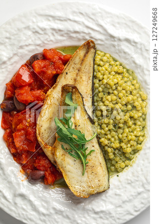 Portion of sea bass fillet with ptitim and tomato Portion of sea bass fillet with ptitim and tomato 127249668