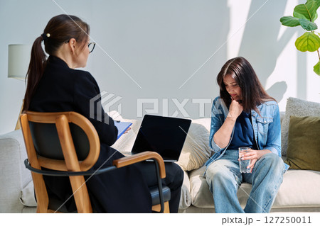 Sad woman patient at mental therapy session, talking with psychologist 127250011
