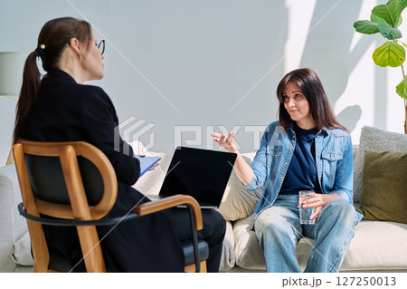 Young woman patient at mental therapy session, talking with psychologist 127250013