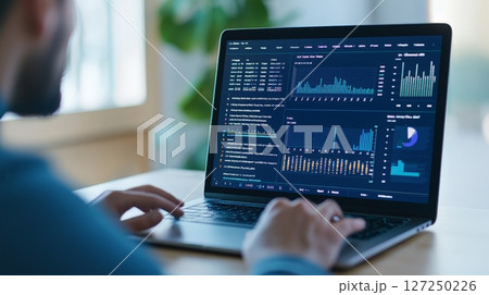Man Analyzing Financial Data on Laptop with Graphs and Charts Displayed on Screen 127250226