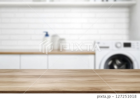 Empty horizontal wooden table for product placement in a laundry room. Flat blank tabletop surface for product display montage or counter with a blurred washing machine background. Fresh laundry. 127251018