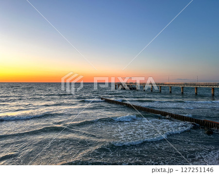 Golden sunset over calm sea with wooden pier stretching into water. Meditation content, moody aesthetics. Golden sunset over calm sea with wooden pier stretching into water. Meditation content, moody aesthetics. 127251146