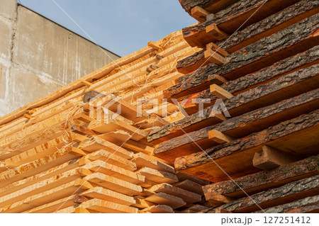 Freshly cut timber is neatly stacked at a construction site, soaking up sunlight in the early afternoon hours for drying 127251412