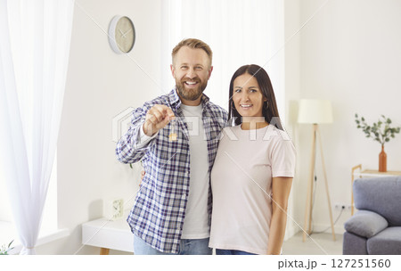 Happy young couple showing keys to camera, husband and wife excited by moving into new modern flat 127251560